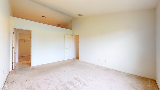 carpeted spare room featuring high vaulted ceiling