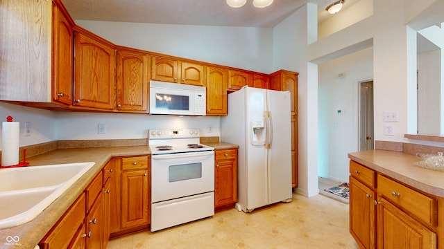 kitchen featuring lofted ceiling, sink, and white appliances