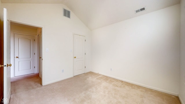 unfurnished room featuring lofted ceiling and light colored carpet