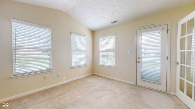 carpeted spare room featuring vaulted ceiling and a textured ceiling