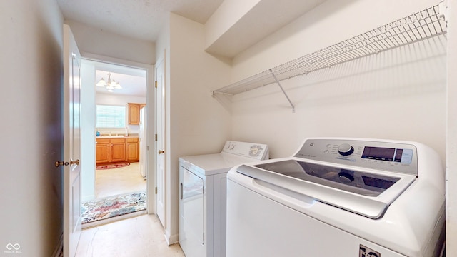 laundry area with an inviting chandelier and separate washer and dryer