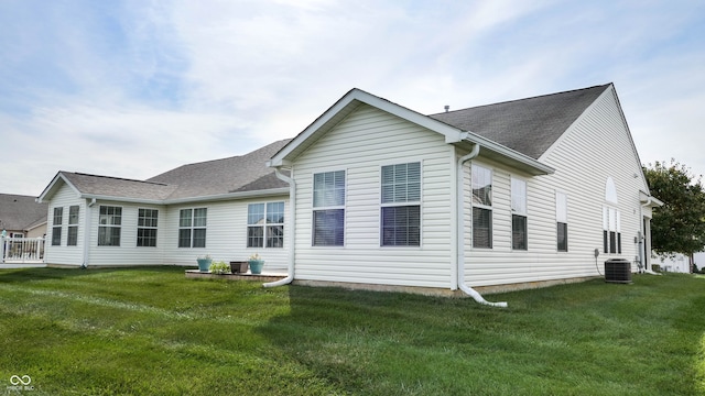 rear view of property with a yard and central air condition unit