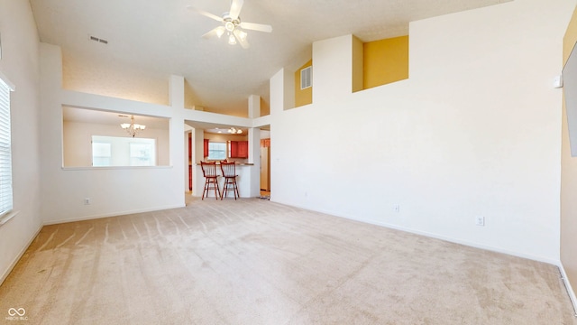 spare room with a high ceiling, carpet floors, and ceiling fan with notable chandelier