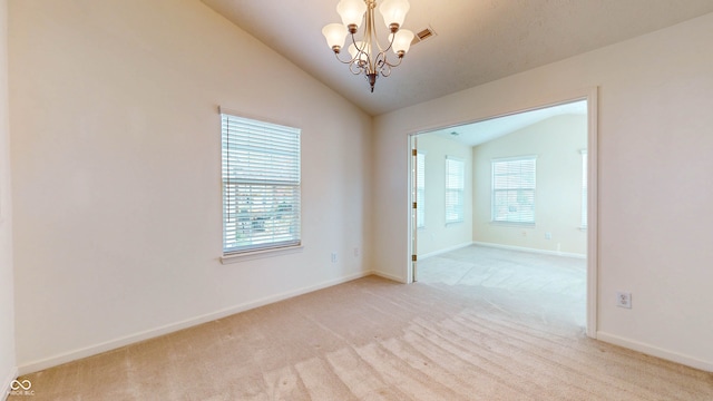 empty room with an inviting chandelier, light colored carpet, and vaulted ceiling