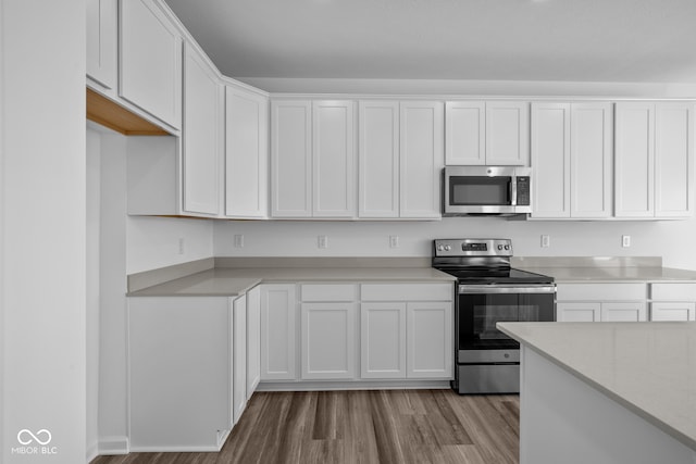 kitchen with light hardwood / wood-style flooring, white cabinets, and stainless steel appliances