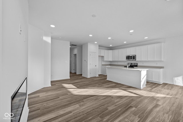 kitchen featuring light hardwood / wood-style flooring, sink, a kitchen island with sink, white cabinetry, and appliances with stainless steel finishes