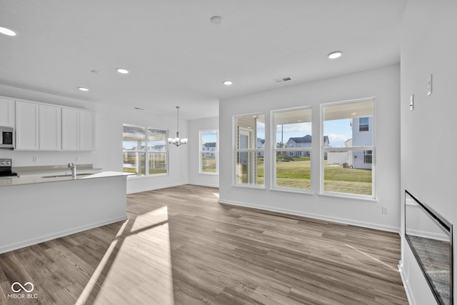 kitchen featuring sink, an inviting chandelier, decorative light fixtures, light hardwood / wood-style flooring, and white cabinets