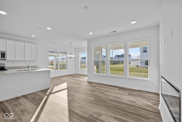 10549 Maidenhair Dr, Indianapolis, IN 46239 - unfurnished living room featuring a sink, recessed lighting, light wood-style floors, a chandelier, and baseboards