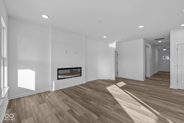 10549 Maidenhair Dr, Indianapolis, IN 46239 - unfurnished living room featuring wood finished floors, recessed lighting, baseboards, and a glass covered fireplace