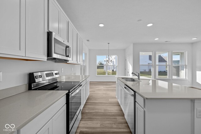 10549 Maidenhair Dr, Indianapolis, IN 46239 - kitchen with appliances with stainless steel finishes, a sink, light wood finished floors, a chandelier, and recessed lighting