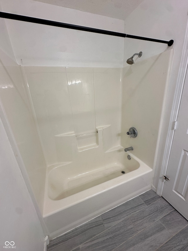 bathroom with hardwood / wood-style flooring and shower / tub combination