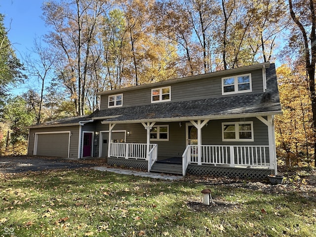 view of front of home featuring covered porch, a garage, and a front lawn