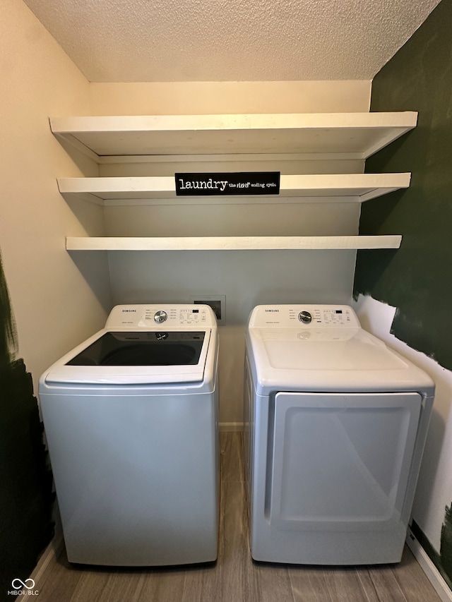 laundry room featuring independent washer and dryer, wood-type flooring, and a textured ceiling