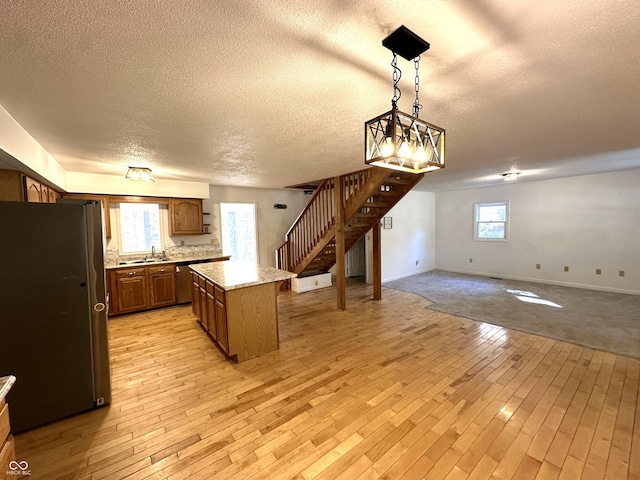 kitchen featuring a textured ceiling, a center island, plenty of natural light, and stainless steel fridge