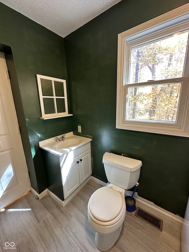 bathroom featuring vanity, hardwood / wood-style floors, toilet, and a textured ceiling