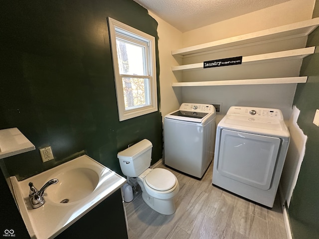 bathroom with a textured ceiling, hardwood / wood-style flooring, separate washer and dryer, toilet, and sink