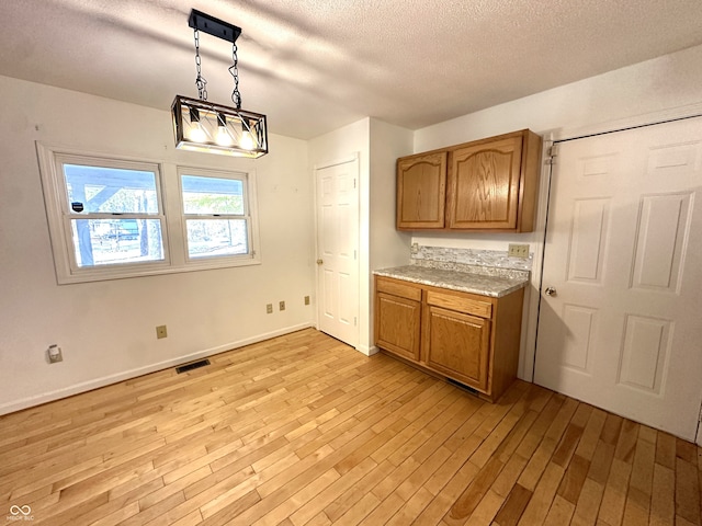 kitchen with light hardwood / wood-style flooring, hanging light fixtures, and a textured ceiling