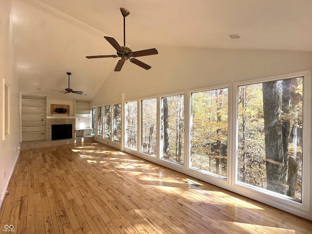 unfurnished sunroom with lofted ceiling, a fireplace, and ceiling fan