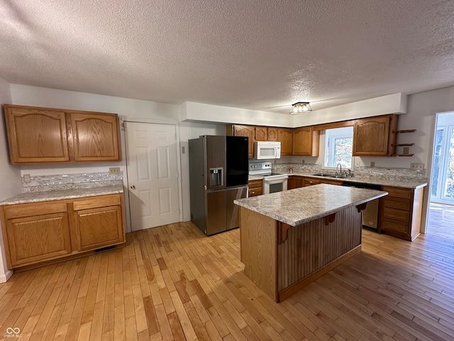 kitchen with a breakfast bar area, a textured ceiling, light wood-type flooring, stainless steel appliances, and a center island