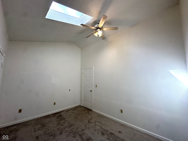 carpeted empty room featuring vaulted ceiling with skylight and ceiling fan