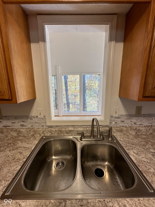 room details with a textured ceiling, sink, and light stone counters