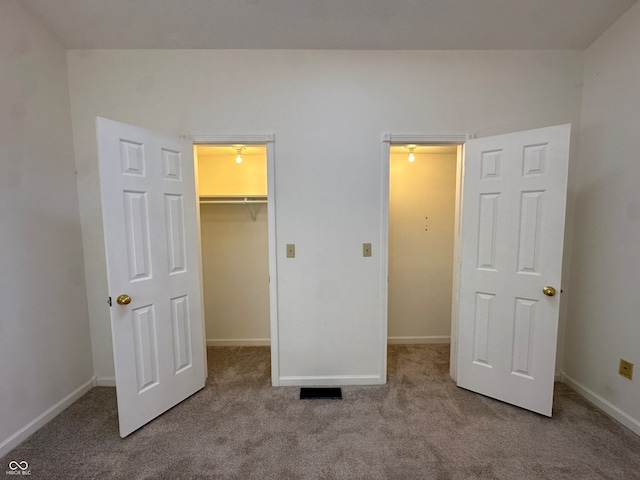 unfurnished bedroom featuring a closet, a spacious closet, and light colored carpet