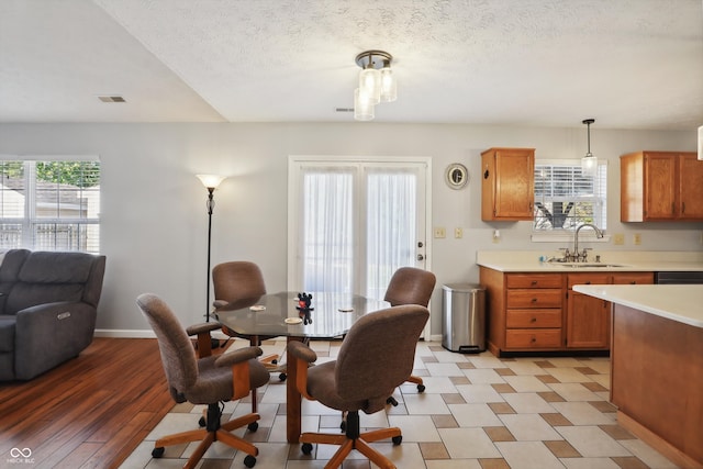 dining space with light hardwood / wood-style floors, a textured ceiling, a healthy amount of sunlight, and sink