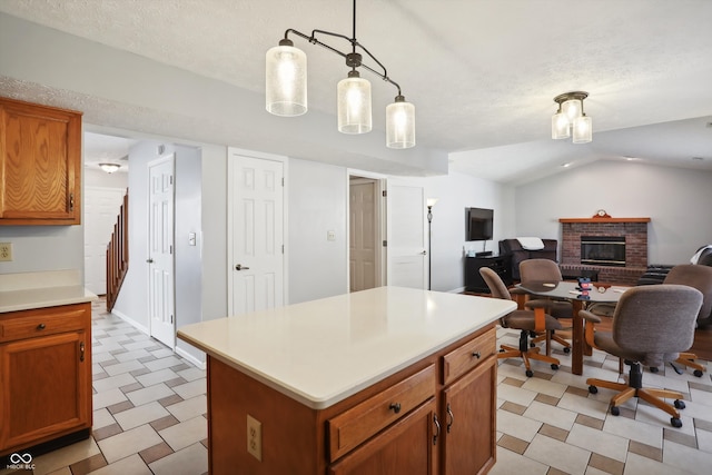 kitchen featuring a textured ceiling, a center island, a brick fireplace, vaulted ceiling, and decorative light fixtures