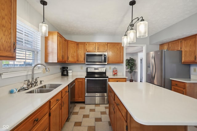 kitchen with hanging light fixtures, appliances with stainless steel finishes, a textured ceiling, sink, and a center island