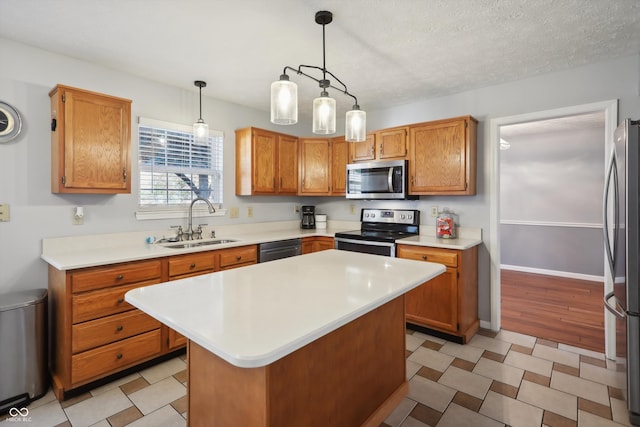 kitchen featuring hanging light fixtures, stainless steel appliances, sink, a center island, and a textured ceiling