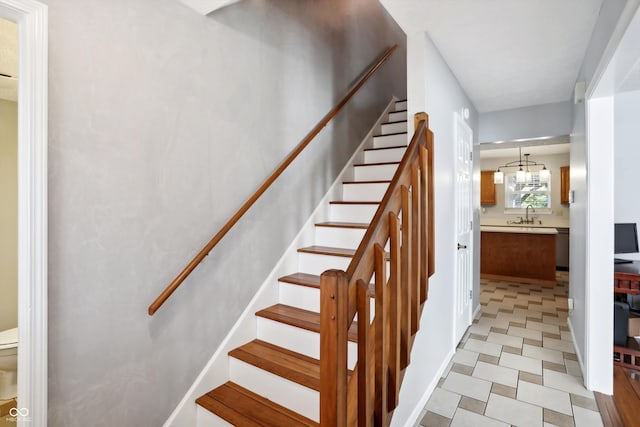 stairway with sink and an inviting chandelier