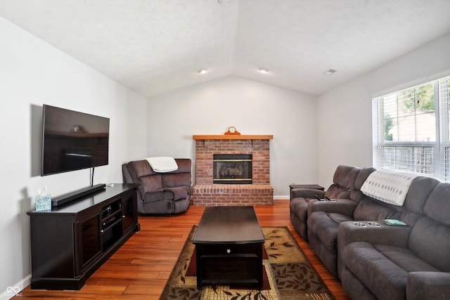 living room with a textured ceiling, vaulted ceiling, a fireplace, and hardwood / wood-style floors