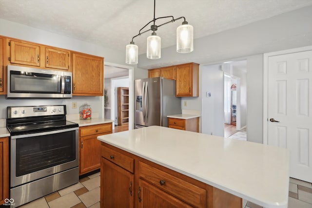 kitchen featuring appliances with stainless steel finishes, a textured ceiling, decorative light fixtures, and a kitchen island