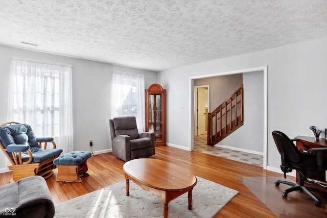 living room with light hardwood / wood-style flooring, a textured ceiling, and plenty of natural light