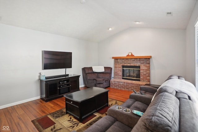 living room featuring wood-type flooring, lofted ceiling, and a fireplace