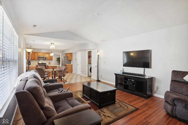 living room featuring washer / dryer, dark hardwood / wood-style floors, and vaulted ceiling