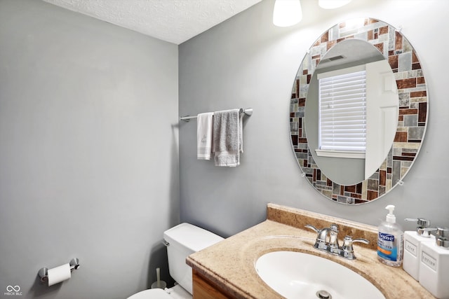 bathroom with vanity, toilet, and a textured ceiling