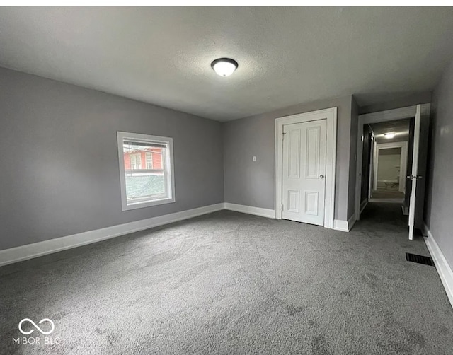 unfurnished bedroom featuring dark colored carpet and a textured ceiling