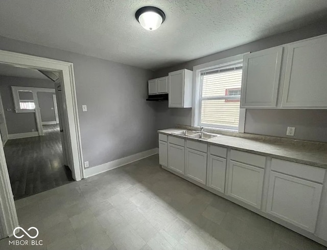 kitchen with white cabinetry, a textured ceiling, and sink