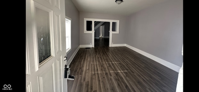 hall with a healthy amount of sunlight and dark hardwood / wood-style flooring