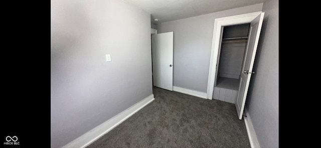 interior space featuring dark colored carpet and a closet