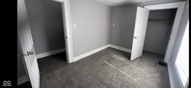 unfurnished bedroom with dark carpet and a closet