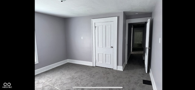 unfurnished bedroom with dark colored carpet and a textured ceiling