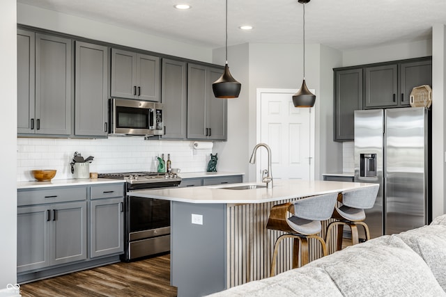 kitchen featuring hanging light fixtures, dark hardwood / wood-style flooring, appliances with stainless steel finishes, gray cabinetry, and sink