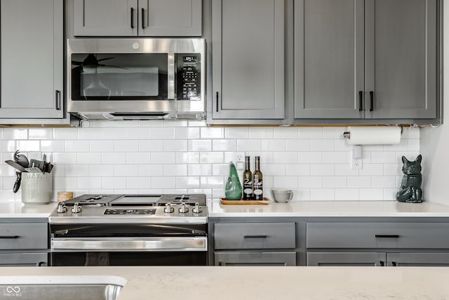 kitchen featuring gray cabinets, appliances with stainless steel finishes, and tasteful backsplash