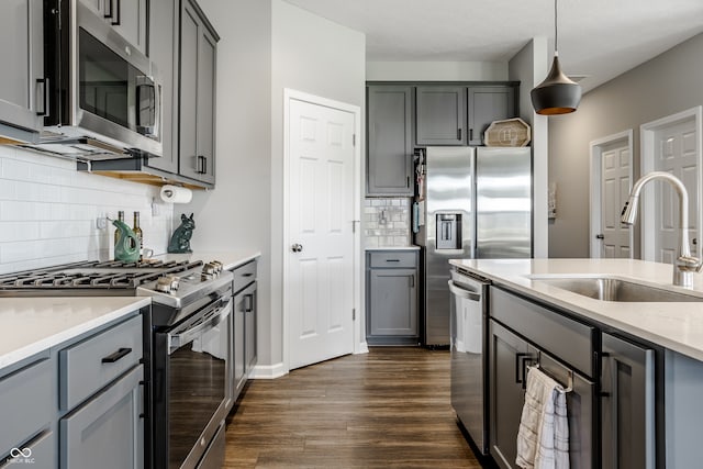 kitchen featuring dark hardwood / wood-style floors, sink, decorative light fixtures, gray cabinets, and appliances with stainless steel finishes