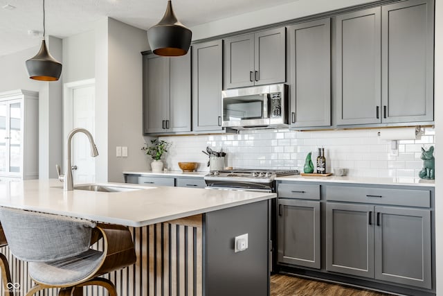 kitchen with sink, appliances with stainless steel finishes, gray cabinetry, and decorative light fixtures