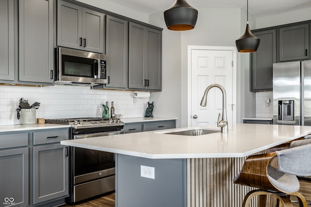 kitchen with gray cabinets, a kitchen island with sink, and stainless steel appliances