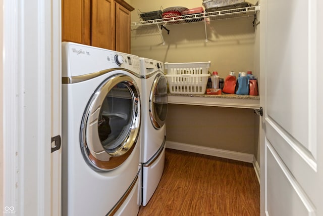 laundry area featuring dark hardwood / wood-style flooring, washing machine and dryer, and cabinets