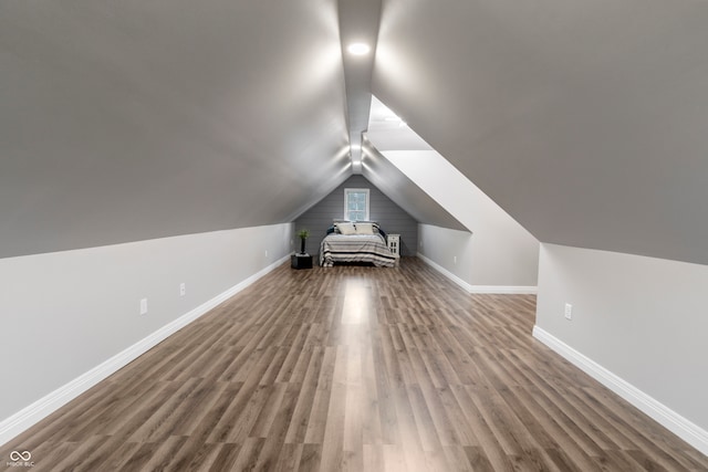 additional living space with wood-type flooring and vaulted ceiling